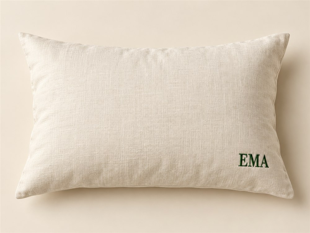 Ivory pillow case with a fictional forest green corner monogram